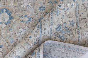 This is an antique Persian Tabriz handwoven carpet in muted blue with ivory tones. This vintage hand woven wool rug features a all over floral design.