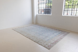 This is an antique Persian Tabriz handwoven carpet in muted blue and pinky red with ivory tones. This vintage hand woven wool rug features a all over floral design.