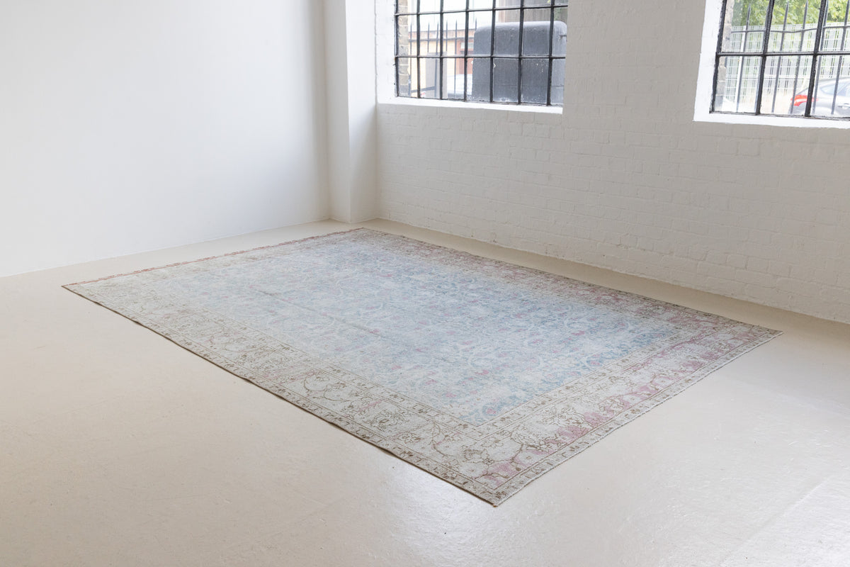 This is an antique Persian Tabriz handwoven carpet in muted blue and pinky red with ivory tones. This vintage hand woven wool rug features a all over floral design.
