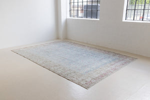 This is an antique Persian Tabriz handwoven carpet in muted blue and pinky red with ivory tones. This vintage hand woven wool rug features a all over floral design.