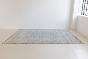 This is an antique Persian Tabriz handwoven carpet in muted blue and pinky red with ivory tones. This vintage hand woven wool rug features a all over floral design.