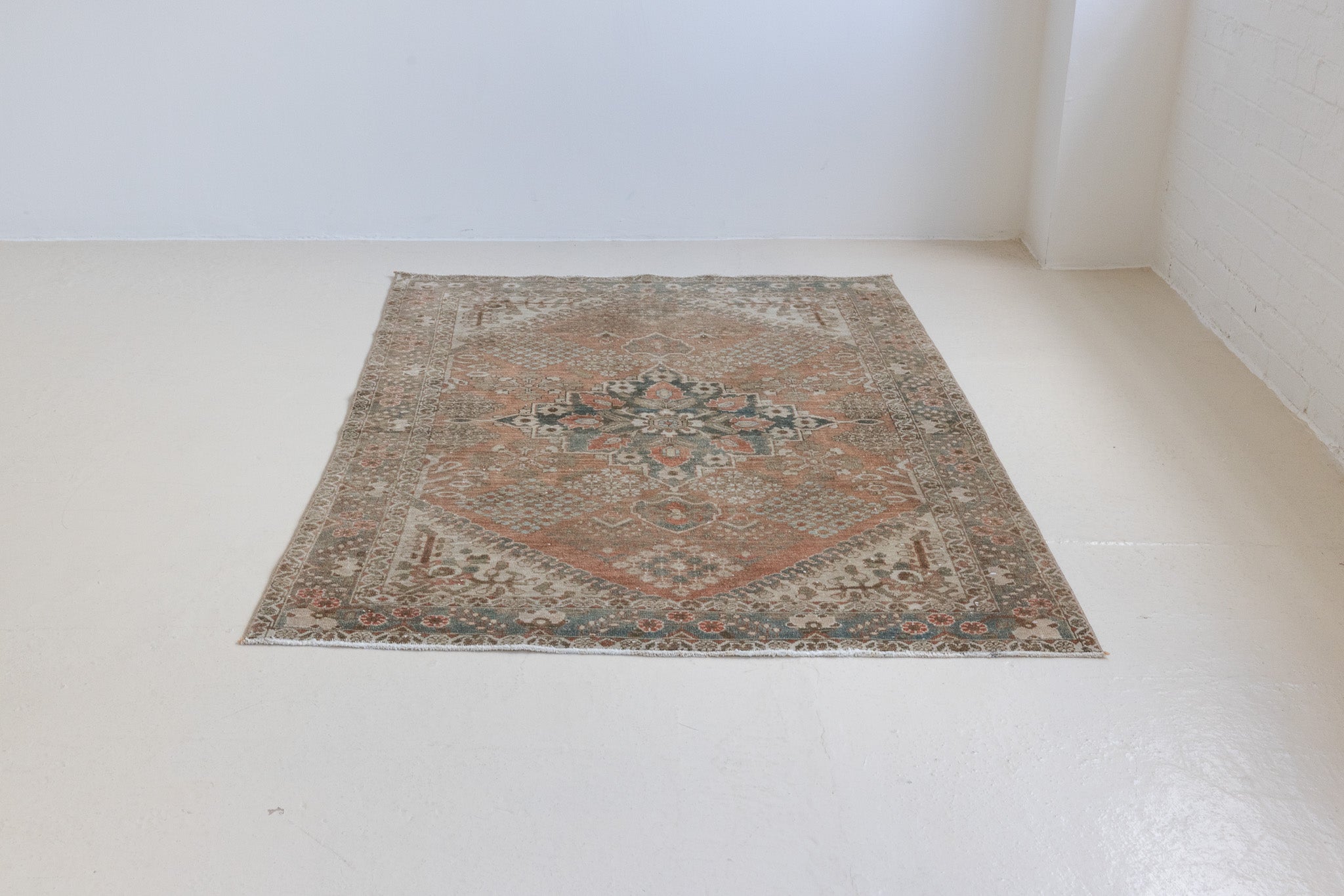 An antique Persian Bakhtiyari rug with a bold medallion in blue, green and terracotta. This handwoven Persian carpet has a  pretty floral border.