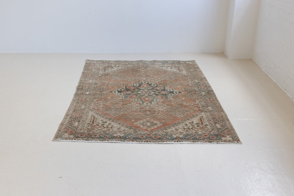 An antique Persian Bakhtiyari rug with a bold medallion in blue, green and terracotta. This handwoven Persian carpet has a  pretty floral border.