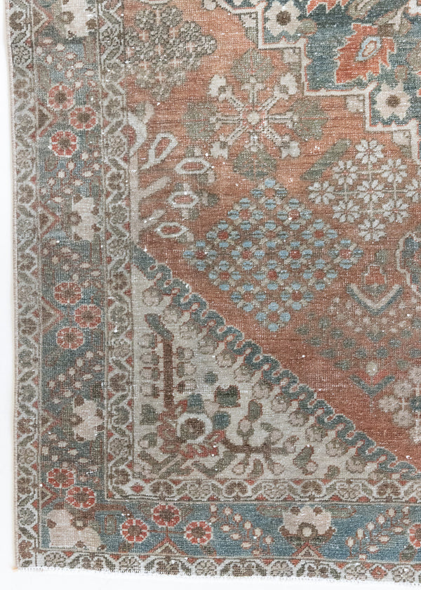 An antique Persian Bakhtiyari rug with a bold medallion in blue, green and terracotta. This handwoven Persian carpet boasts a  pretty floral border.