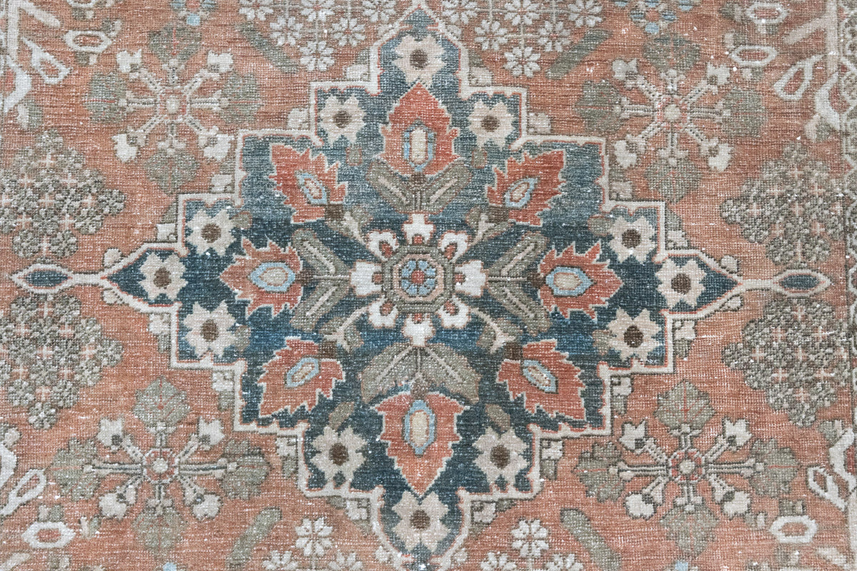 An antique Persian Bakhtiyari rug with a bold medallion in blue, green and terracotta. This handwoven Persian carpet has a  pretty floral border.
