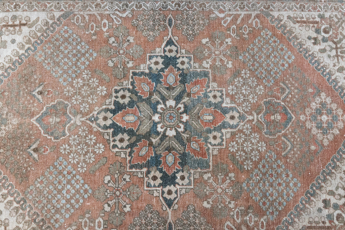 An antique Persian Bakhtiyari rug with a bold medallion in blue, green and terracotta. This handwoven Persian carpet boasts a  pretty floral border.