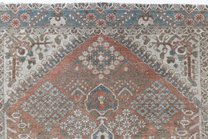 An antique Persian Bakhtiyari rug with a bold medallion in blue, green and terracotta. This handwoven Persian carpet boasts a  pretty floral border.