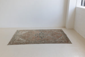 An antique Persian Bakhtiyari rug with a bold medallion in blue, green and terracotta. This handwoven Persian carpet has a  pretty floral border.