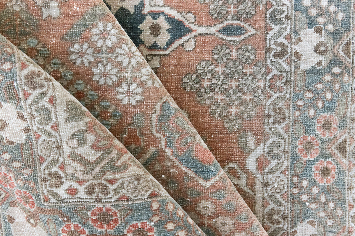 Close up of antique Persian Bakhtiyari rug with a bold medallion in blue, green and terracotta. This handwoven Persian carpet has a  pretty floral border.