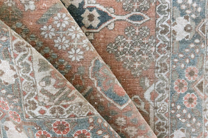 Close up of antique Persian Bakhtiyari rug with a bold medallion in blue, green and terracotta. This handwoven Persian carpet has a  pretty floral border.