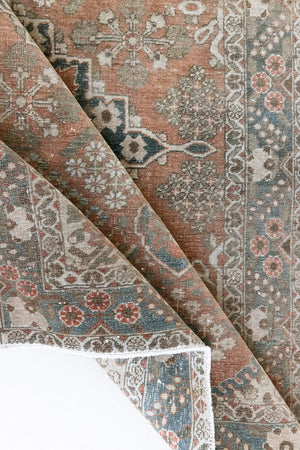 A close up of an antique Persian Bakhtiyari rug with a bold medallion in blue, green and terracotta. This handwoven Persian carpet has a lovely design and a floral border.