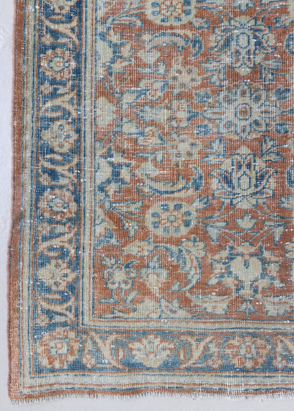 This is an antique Persian Mahal handwoven carpet in a rusty orange red  and muted blue with ivory tones. This vintage hand woven wool rug features a all over floral design.