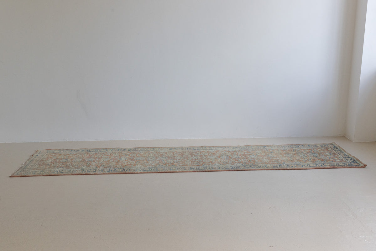This is an large antique Persian Mahal runner handwoven carpet in a rusty orange red  and muted blue with ivory tones. This vintage hand woven wool rug features a all over floral design.