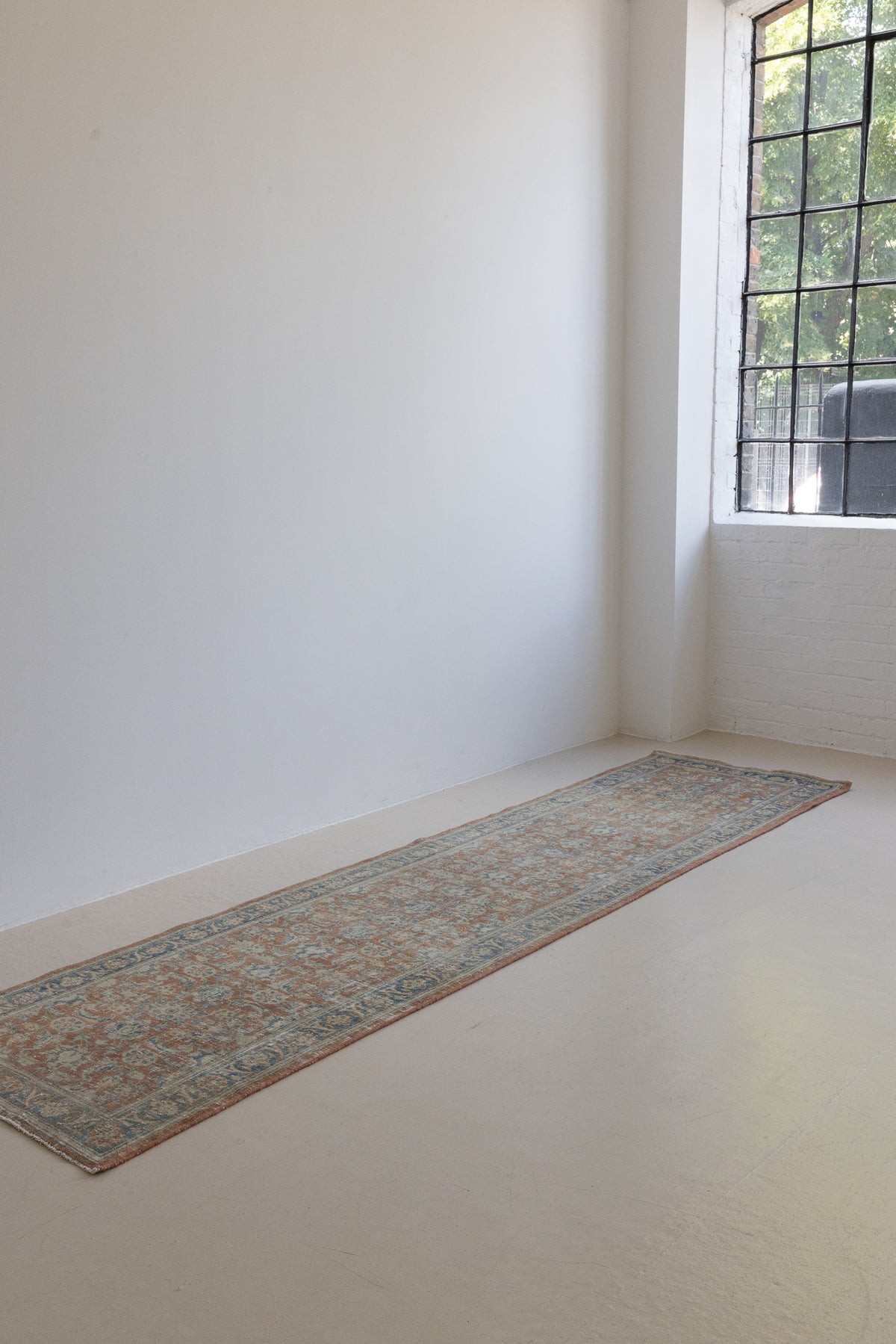 This is an large antique Persian Mahal runner handwoven carpet in a rusty orange red  and muted blue with ivory tones. This vintage hand woven wool rug features a all over floral design.