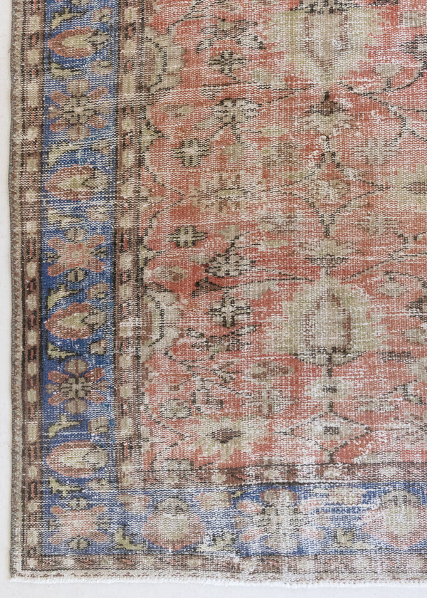 This is an large antique Turkish handwoven carpet in a rusty orange red  and muted blue with ivory tones. This vintage hand woven wool rug features a all over floral design.