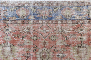 This is an large antique Turkish handwoven carpet in a rusty orange red  and muted blue with ivory tones. This vintage hand woven wool rug features a all over floral design.