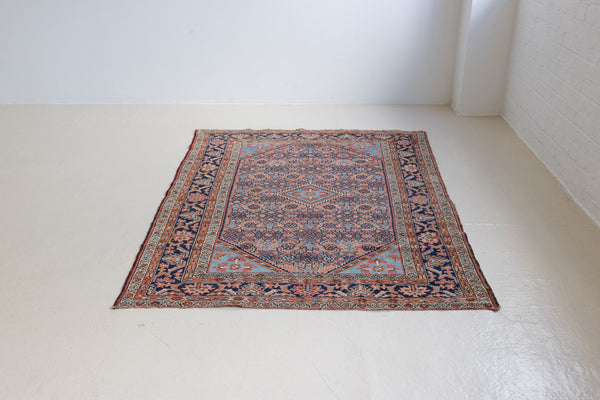 An antique Persian Malayer rug, woven in the north west of Iran. This pretty Persian handwoven carpet features a fine all-over pattern in soft pink, dusty blue and navy. The Malayer region is known for producing some of the most ornate Persian rugs, often known for their mesmerising and intricate patterns.