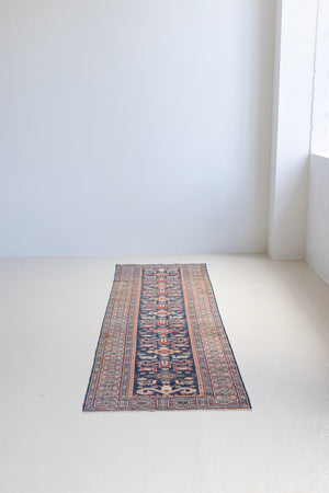 Beau is an antique Persian Caucasian runner in red and cream on a deep indigo ground. Handwoven Caucasian carpets are celebrated for their bold geometric patterns and rich, saturated and jewel tones. 