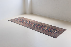 Beau is an antique Persian Caucasian runner in red and cream on a deep indigo ground, framed by a wide geometric border. Handwoven Caucasian carpets are prized for their bold geometric patterns and rich, saturated and jewel tones. 
