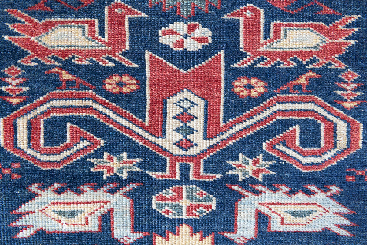 Beau is an antique Persian Caucasian runner in red and cream on a deep indigo ground, framed by a wide geometric border. Handwoven Caucasian carpets are prized for their bold geometric patterns and rich, saturated and jewel tones. 