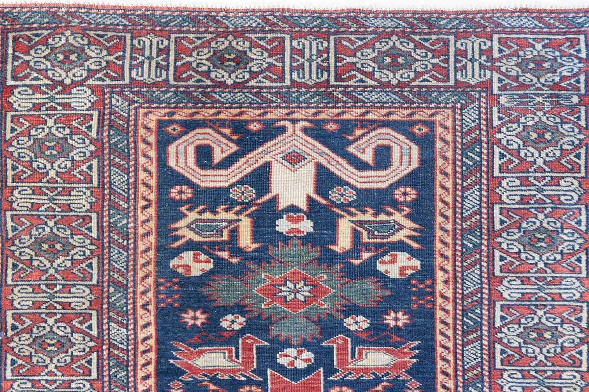 Beau is an antique Persian Caucasian runner in red and cream on a deep indigo ground, framed by a wide geometric border. Handwoven Caucasian carpets are prized for their bold geometric patterns and rich, saturated and jewel tones. 
