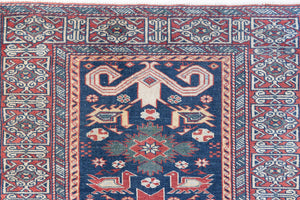 Beau is an antique Persian Caucasian runner in red and cream on a deep indigo ground, framed by a wide geometric border. Handwoven Caucasian carpets are prized for their bold geometric patterns and rich, saturated and jewel tones. 