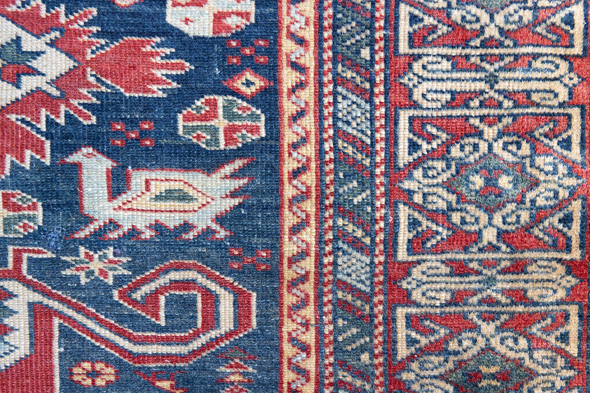 Beau is an antique Persian Caucasian runner in red and cream on a deep indigo ground, framed by a wide geometric border. Handwoven Caucasian carpets are prized for their bold geometric patterns and rich, saturated and jewel tones. 