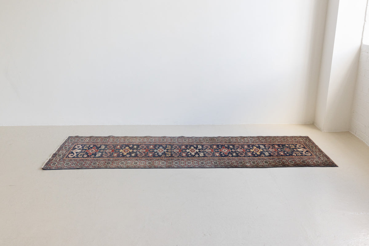 Beau is an antique Persian Caucasian runner in red and cream on a deep indigo ground, framed by a wide geometric border. Handwoven Caucasian carpets are prized for their bold geometric patterns and rich, saturated and jewel tones. 