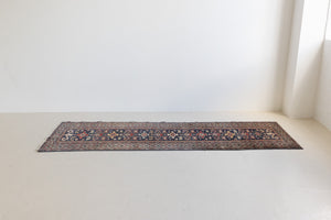 Beau is an antique Persian Caucasian runner in red and cream on a deep indigo ground, framed by a wide geometric border. Handwoven Caucasian carpets are prized for their bold geometric patterns and rich, saturated and jewel tones. 