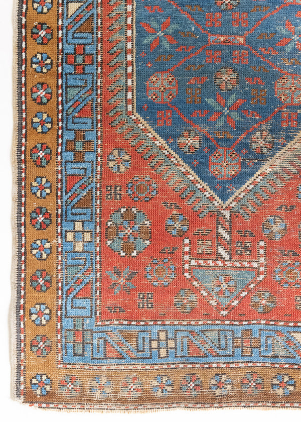 An antique Persian Heriz runner with three medallions in indigo blue set on a rust red field. Heriz rugs is one of the most recognisable Persian carpet designs, known for bold geometric pattern and vibrant colour.