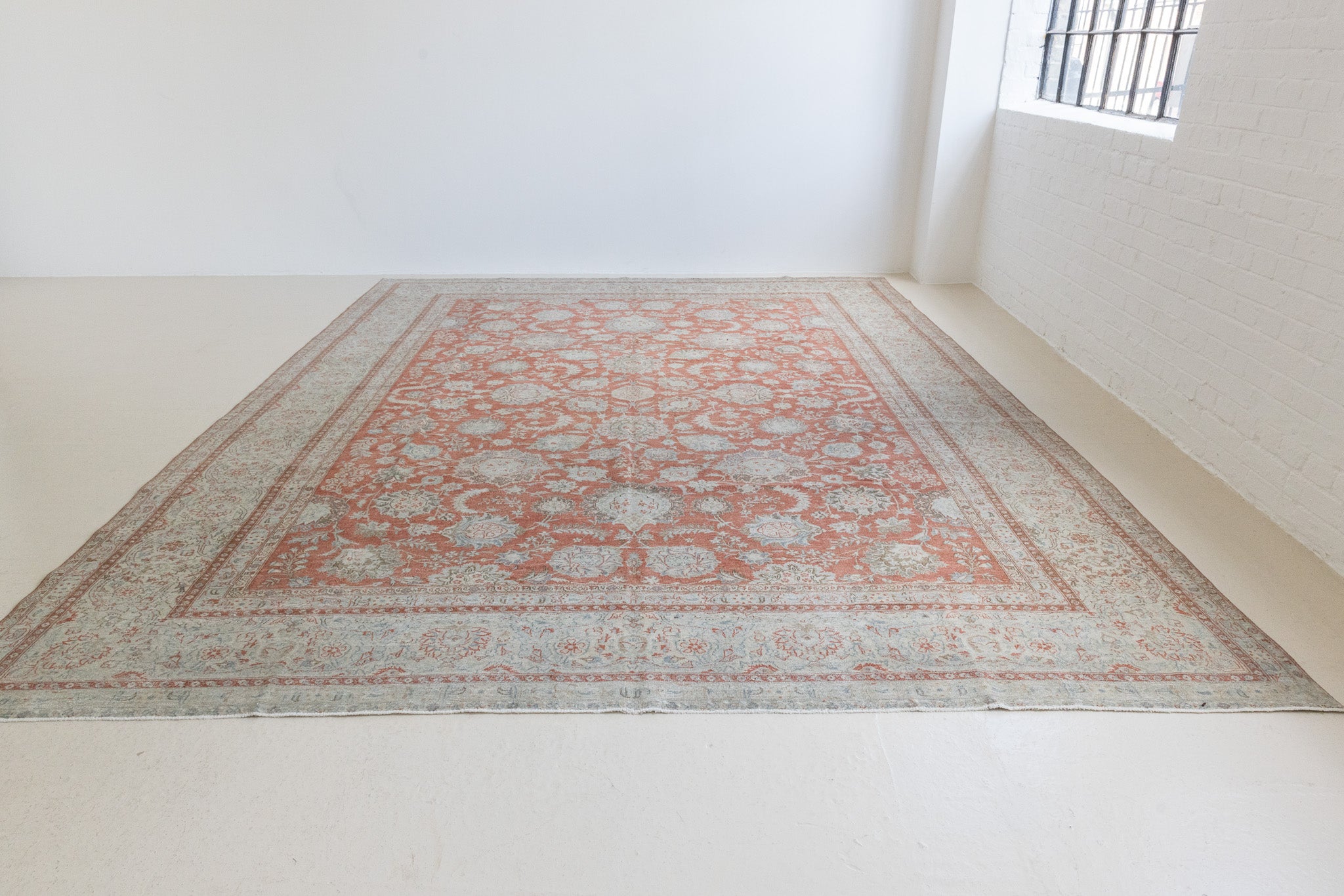 This is an antique Persian Kashan handwoven carpet in blue red and ivory tones. This hand woven wool antique rug features a all over floral design.
