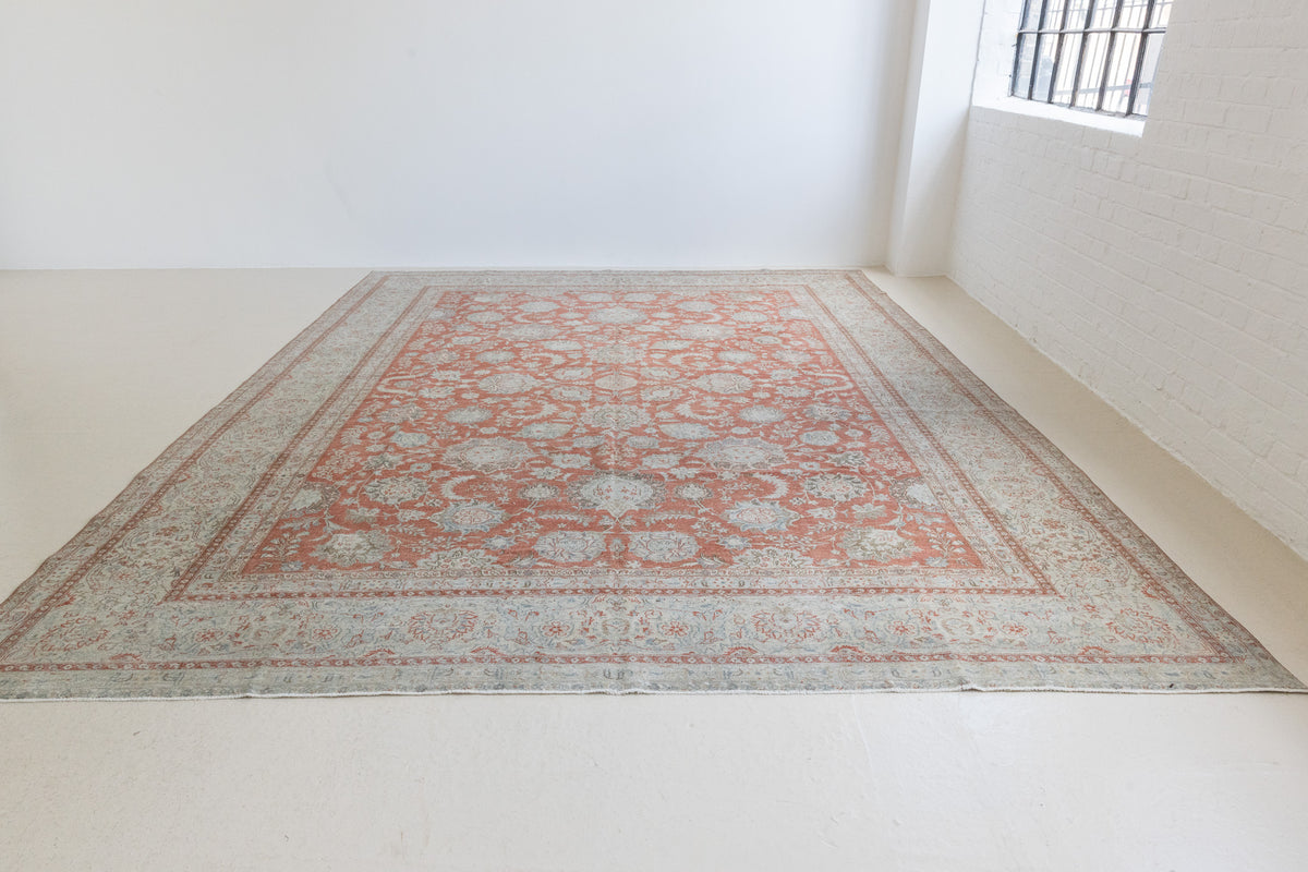 This is an antique Persian Kashan handwoven carpet in blue red and ivory tones. This hand woven wool antique rug features a all over floral design.