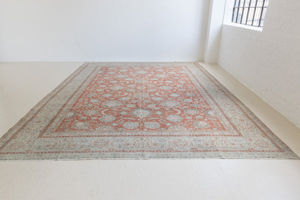 This is an antique Persian Kashan handwoven carpet in blue red and ivory tones. This hand woven wool antique rug features a all over floral design.