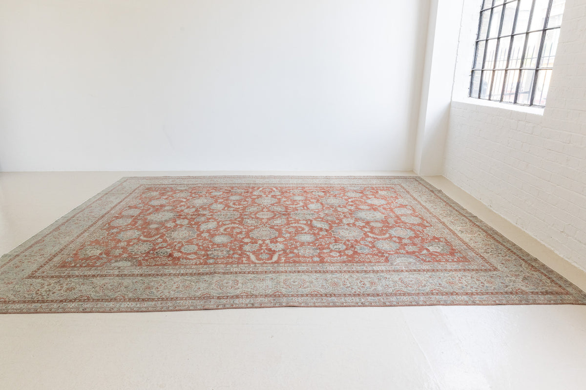 This is an antique Persian Kashan handwoven carpet in blue red and ivory tones. This handmade antique rug features an all over floral design.