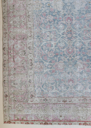 An antique Persian Tabriz rug. This large handwoven antique carpet features a lovely muted blue colour palette and a pink border alongside an intricate all over design.