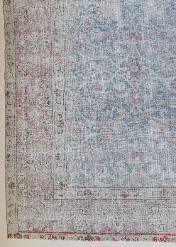 An antique Persian Tabriz rug. This large handwoven antique carpet features a lovely muted blue colour palette and a pink border alongside an intricate all over design.