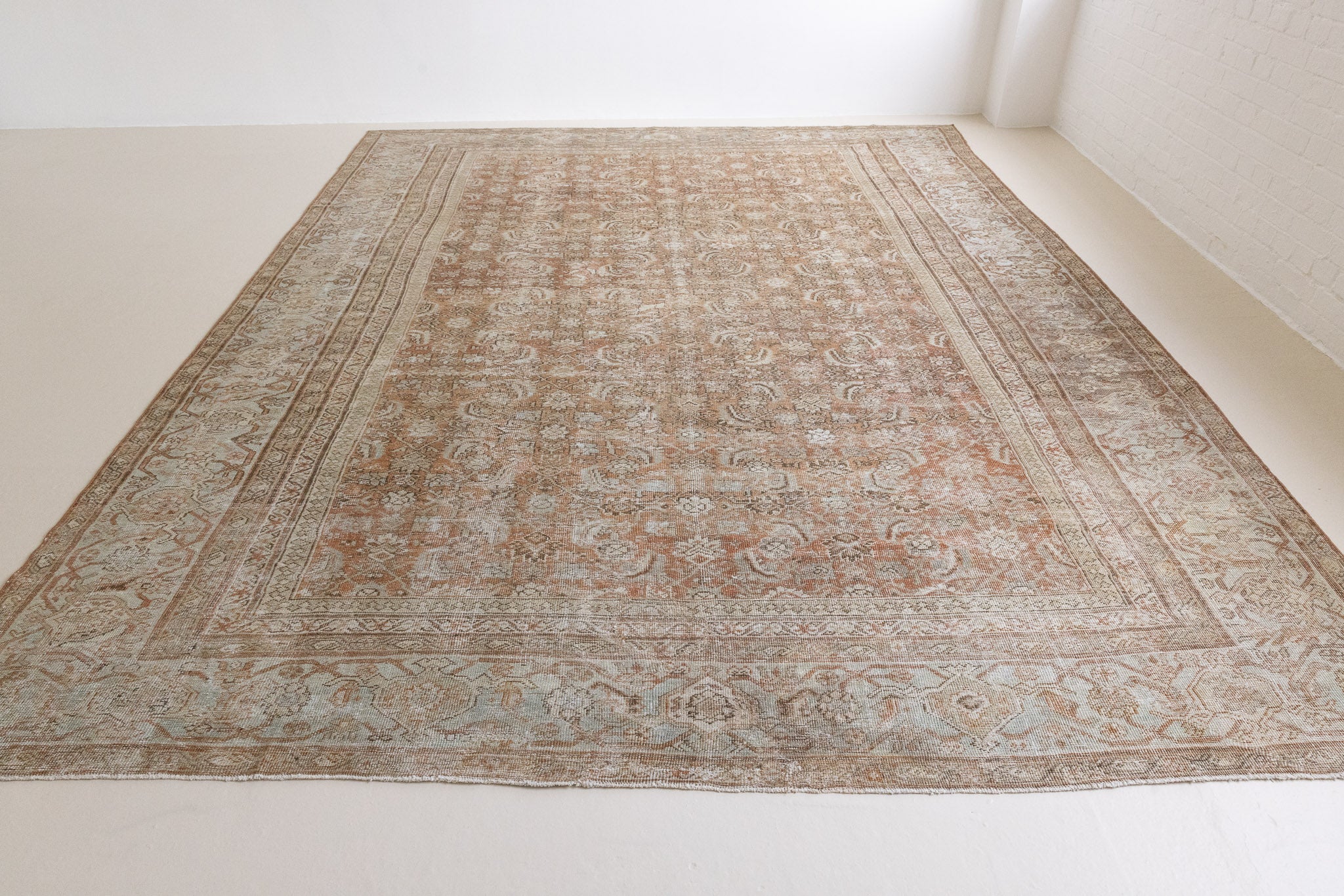 A vintage Persian Mahal carpet in rust and teal tones — this hand-knotted antique rug showcases an all-over floral design.