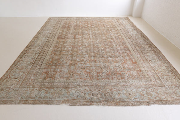A vintage Persian Mahal carpet in rust and teal tones — this hand-knotted antique rug showcases an all-over floral design.