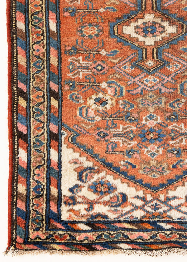 This is an antique Persian Hamedan rug, a handmade carpet in terracotta tones, featuring a central medallion design.
