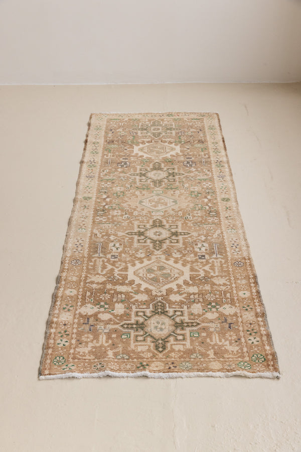 A vintage Persian Heriz runner in taupe, brown and green tones — this hand-knotted antique carpet showcases a Karaja design.
