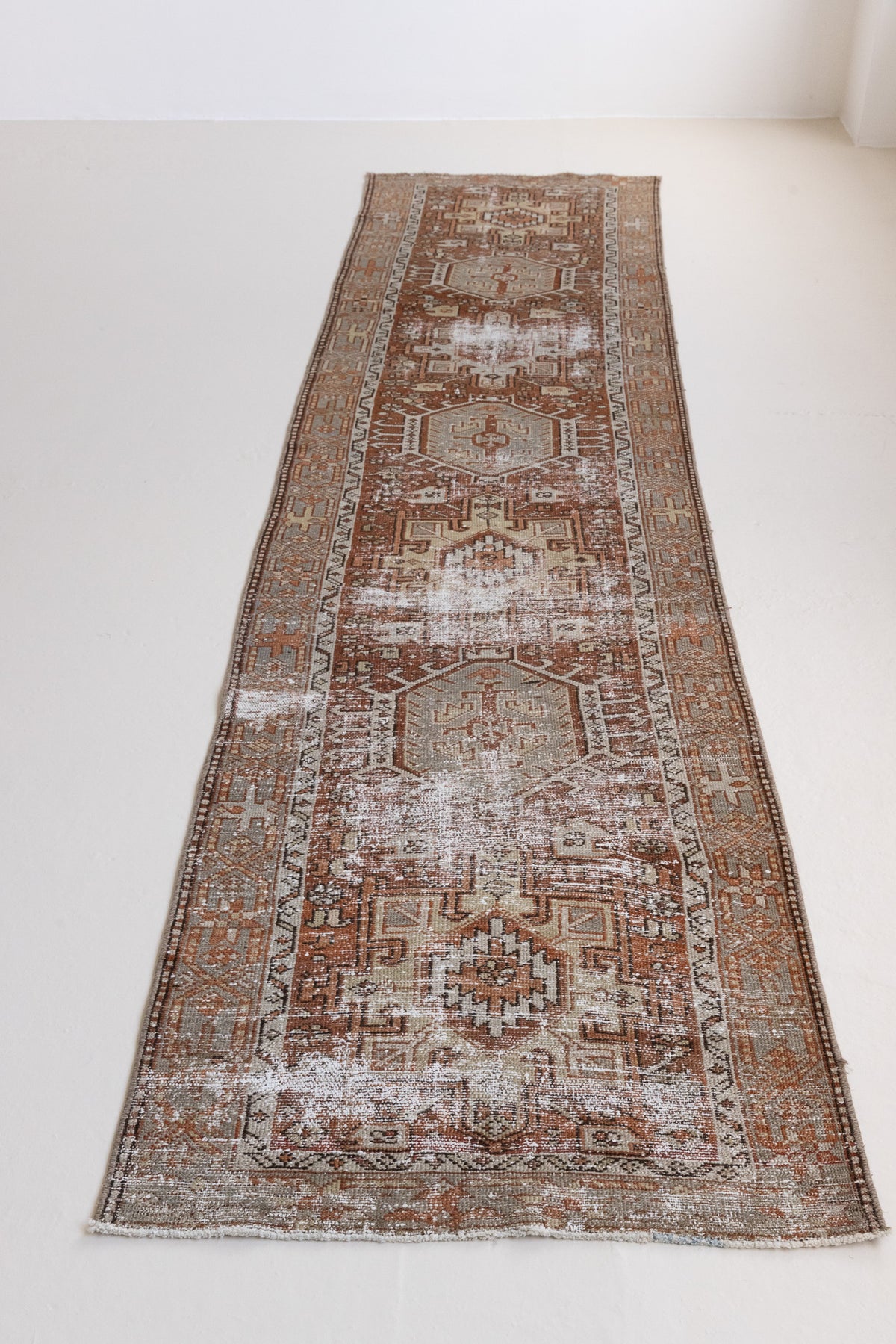 Detail of a genuine antique Persian Heriz runner in red and green tones, a handmade carpet with a Karaja design.