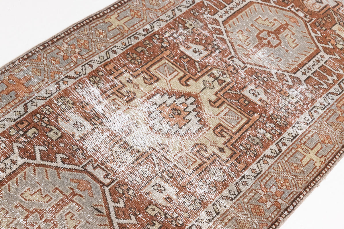 This is an antique Persian Heriz runner, a handmade rug in red and green tones, featuring a Karaja design.