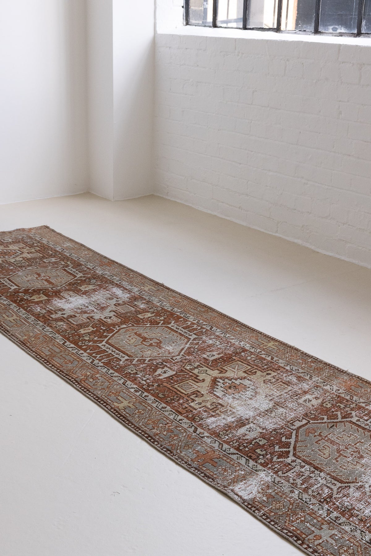 This is an antique Persian Heriz runner, a handmade rug in red and green tones, featuring a Karaja design.