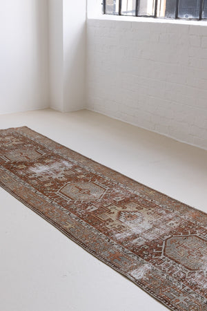 This is an antique Persian Heriz runner, a handmade rug in red and green tones, featuring a Karaja design.