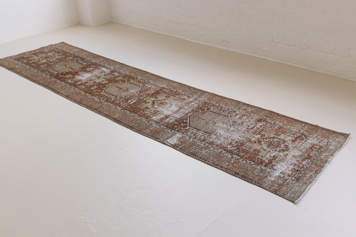 A vintage Persian Heriz runner in red and green tones — this hand-knotted antique carpet showcases a Karaja design.