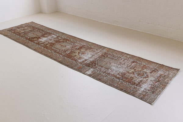 A vintage Persian Heriz runner in red and green tones — this hand-knotted antique carpet showcases a Karaja design.