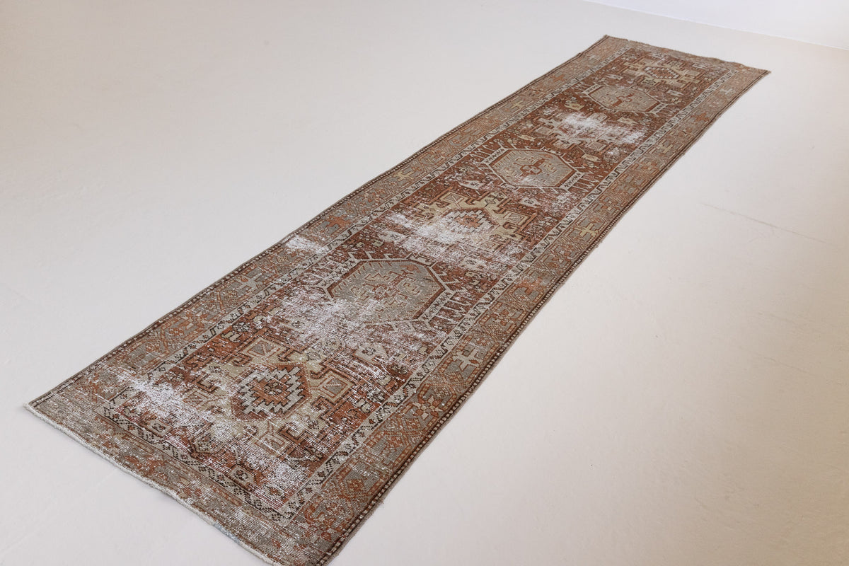 Detail of a genuine antique Persian Heriz runner in red and green tones, a handmade carpet with a Karaja design.