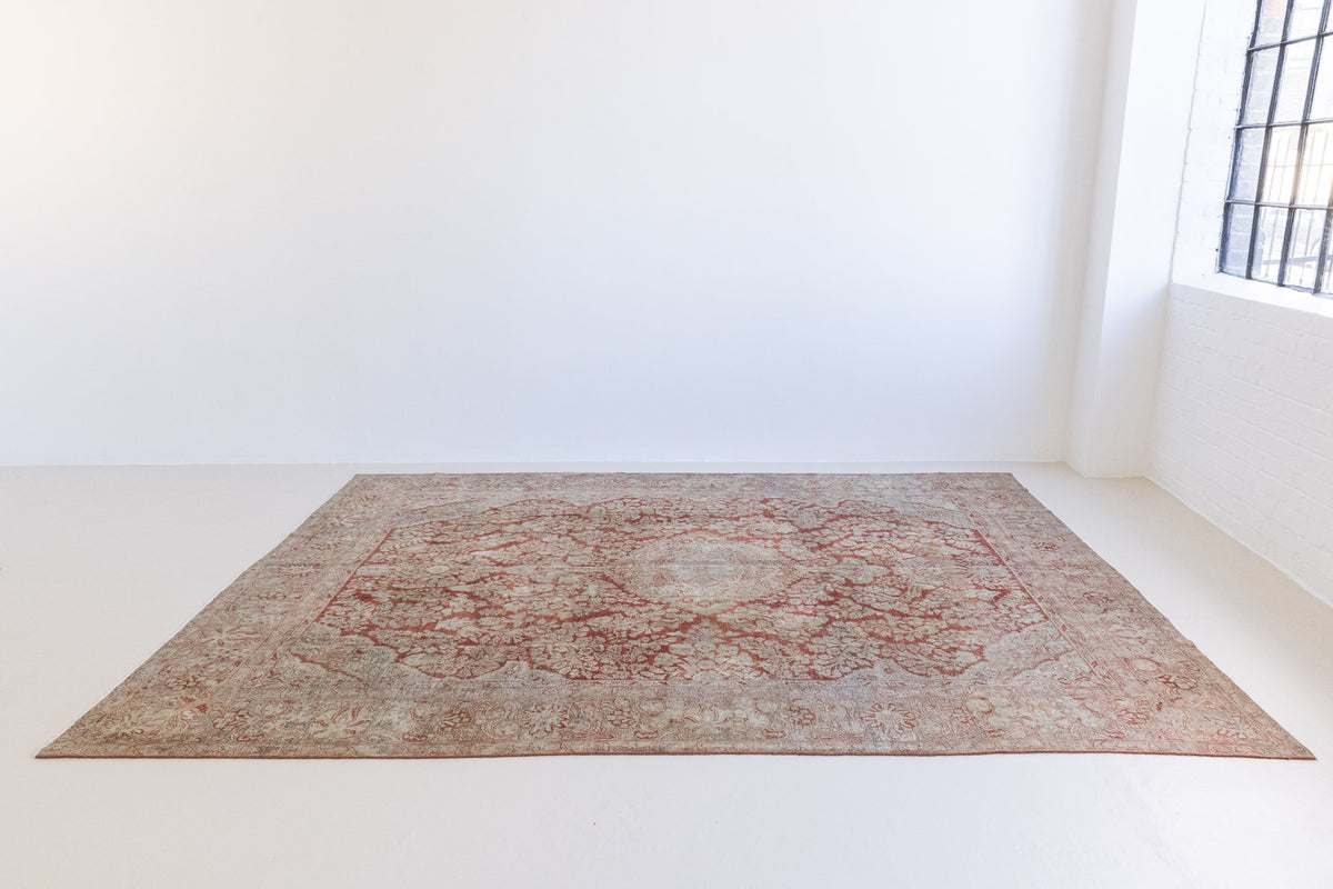 This is an antique Persian Sarouk rug, a handmade carpet in red and blue tones, featuring a floral medallion design.