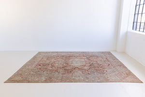 This is an antique Persian Sarouk rug, a handmade carpet in red and blue tones, featuring a floral medallion design.