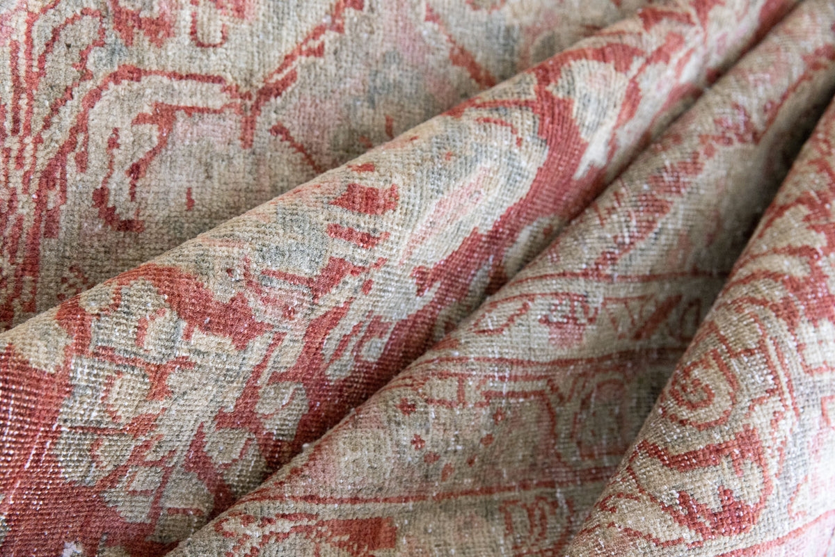 This is an antique Persian Sarouk rug, a handmade carpet in red and blue tones, featuring a floral medallion design.